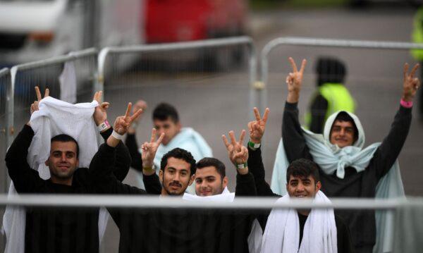 Detainees inside the Manston short-term holding centre for illegal immigrants wave to members of the media outside, near Ramsgate, Kent, southeast England, on Nov. 3, 2022. (Daniel Leal /AFP via Getty Images)