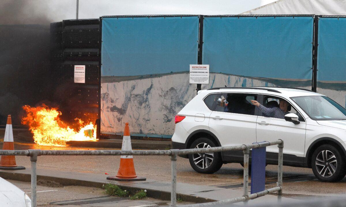 A man throws an object out of a car window next to the Border Force centre after a firebomb attack in Dover, Kent, England, on Oct. 30, 2022. (Peter Nicholls/Reuters)