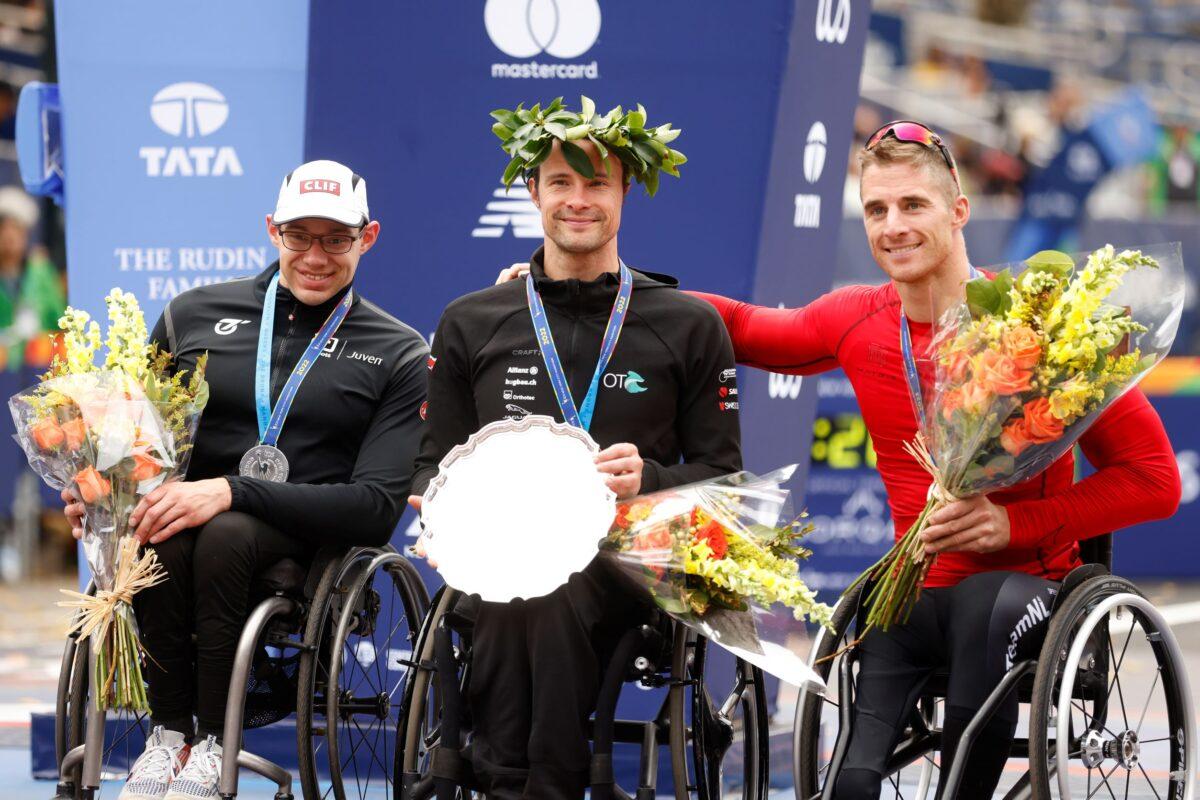 (L–R) Men's wheelchair division second place finisher Daniel Romanchuk of the United States, winner Marcel Hug of Switzerland, and third place finisher Jetze Plat of the Netherlands pose during a ceremony at the finish line of the New York City Marathon in New York on Nov. 6, 2022. (Jason DeCrow/AP Photo)