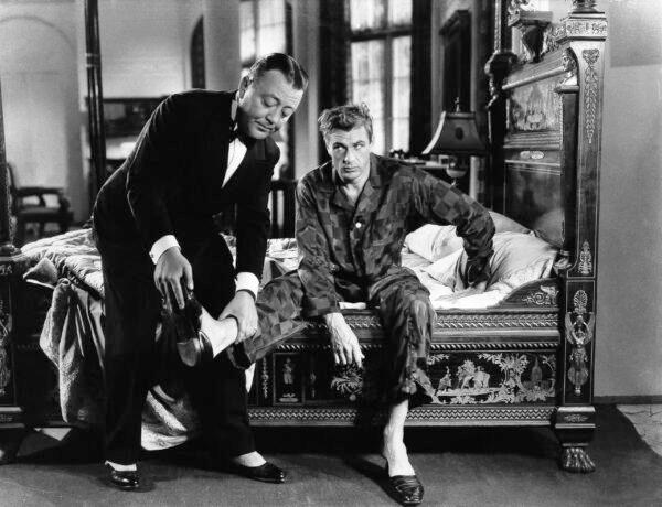 Deed's new butler, Walter (Raymond Walburn), removes shoes from his employer after a night on the town, in "Mr. Deeds Goes to Town." (MovieStillsDB)