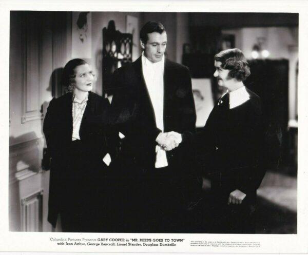 (L–R) Babe Bennett (Jean Arthur) christens Longfellow Deeds (Gary Cooper) as "Cinderella Man" and watches him shake hands with Mabel Dawson (Ruth Donnelly), in "Mr. Deeds Goes to Town." (MovieStillsDB)