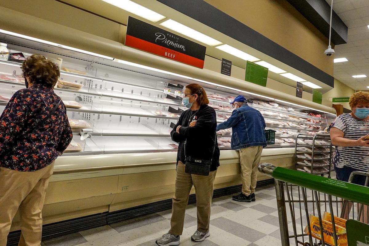Shelves displaying meat are partially empty as shoppers makes their way through a supermarket on in Miami, Fla., on Jan. 11, 2022. (Joe Raedle/Getty Images)