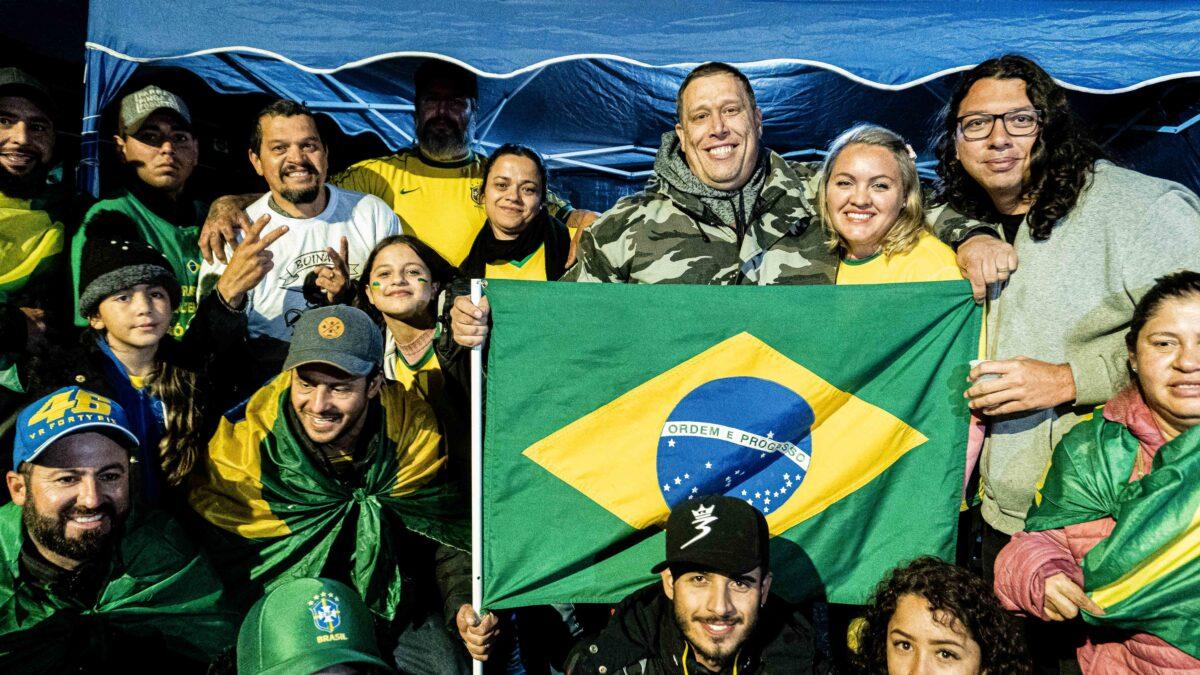 Ivo, third from right to left on the top row, holds a Brazilian flag surrounded by protesters near the Pinheirinho Fortress in Curitiba, Brazil, on Nov. 4, 2022. A former member of the military, he was one of the early starters of the 24/7 protests in southern Brazil, spontaneously setting a tent on Oct. 30, just as the votes were counted. (Frederico Vidovix/The Epoch Times)