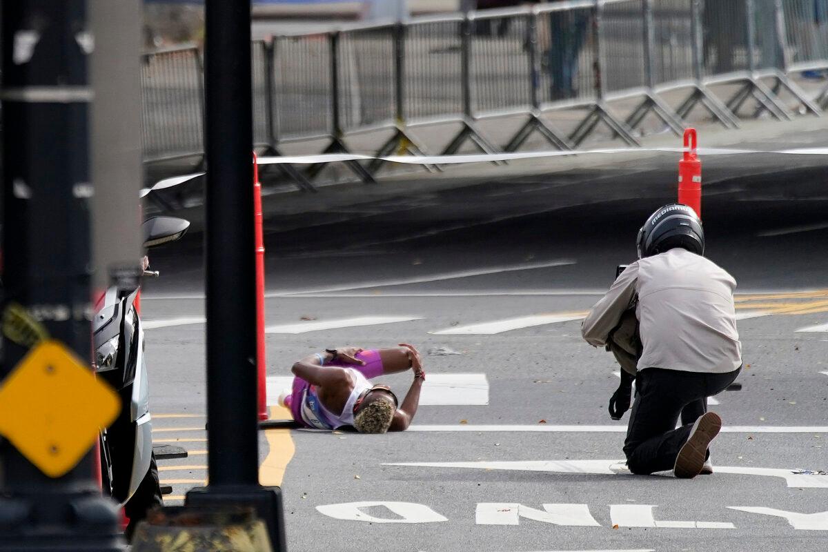 Daniel Do Nascimento of Brazil (L) lays on the pavement after collapsing in the Bronx borough during the New York City Marathon in New York on Nov. 6, 2022. (Julia Nikhinson/AP Photo)