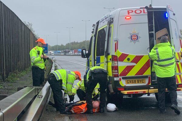 Police officers detain a Just Stop Oil protester who had climbed a gantry on the M25 in Surrey, England, on Nov. 7, 2022. (PA Media/Surrey Police)