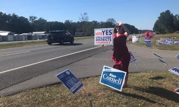 Dana, a nurse practitioner, waves a sign encouraging single-member districts for local government boards in Alachua County, Fla., on Nov. 8, 2022. She didn't want her full name disclosed out of fear of retribution for backing a conservative-led initiative. (Nanette Holt/The Epoch Times)