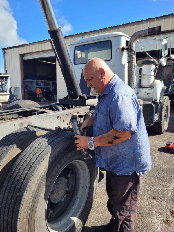 Truck driver Jack Adamo, of Punta Gorda, Fla., speaks of election integrity worries as he works on a tire on Nov. 8, 2022. (Jann Falkenstern/The Epoch Times)