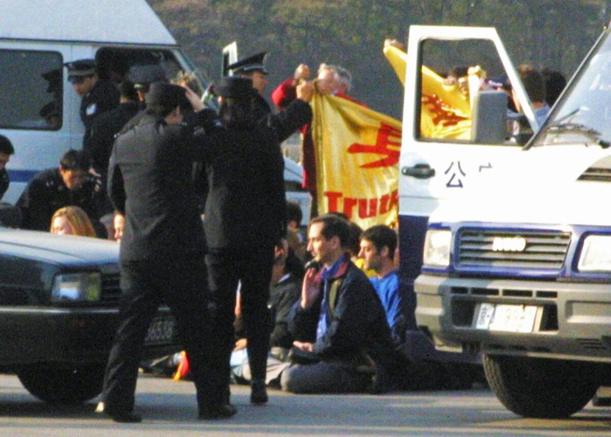 The 36 Falun Gong practitioners from 12 countries are surrounded by Chinese police officers and police vehicles in Tiananmen Square after unfurling a banner reading "Truth - Compassion - Tolerance" and sitting in a meditation position on Nov. 20, 2001. The group was later taken away and detained by police. (AP Photo/Ng Han Guan)