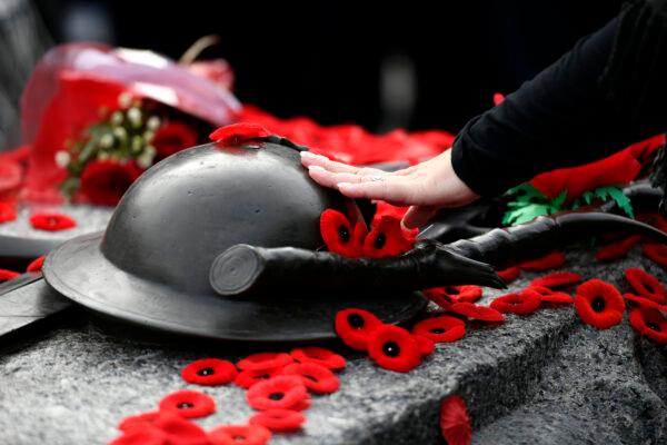 A person touches the helmet on the Tomb of the Unknown Soldier after laying a poppy, at the National War Memorial after the National Remembrance Day Ceremony in Ottawa, on Nov. 11, 2022. (The Canadian Press/Justin Tang)