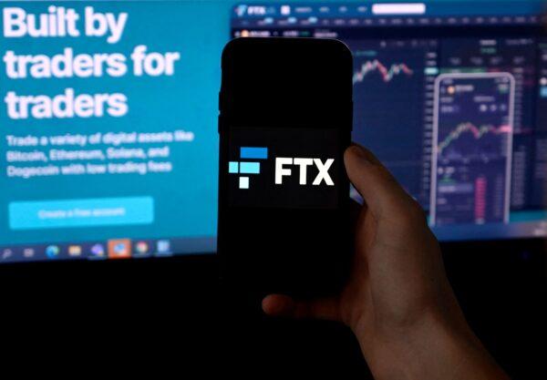This illustration photo shows a smartphone screen displaying the logo of FTX, the crypto exchange platform, with a screen showing the FTX website in the background in Arlington, Va., on Feb. 10, 2022. (Olivier Douliery/AFP via Getty Images)