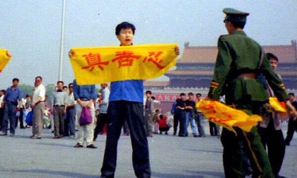  A Chinese police officer approaches a Falun Gong practitioner who is holding a banner bearing the Chinese characters for “truthfulness, compassion, and tolerance,” the core tenets of the Falun Gong spiritual practice, on Tiananmen Square in Beijing. (Courtesy of Minghui.org)