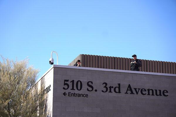 Two police officers stand vigil perched near the roof of the Maricopa County Tabulation and Election Center in Phoenix, Ariz., on Nov. 14, 2022. (Allan Stein/The Epoch Times)