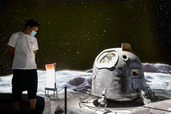 A visitor looks at the model of the lunar landing return capsule during Explore CASCI (China Aerospace Science and Cultural Innovation) ART Exhibition in Wuhan, China, on Oct. 2, 2022. (Getty Images）