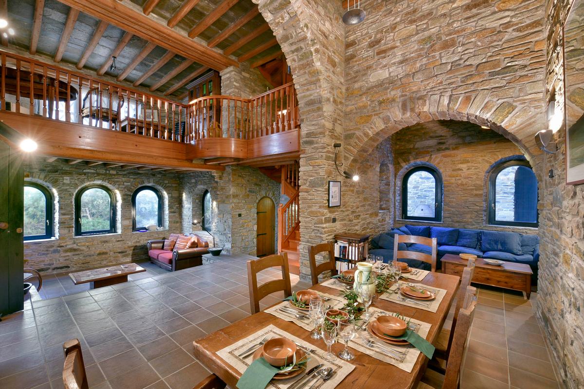 The main residence is laid out on a ground floor and a mezzanine level, all accented by impressive stonework and exposed ceiling beams. (Courtesy of Greece Sotheby’s International Realty)