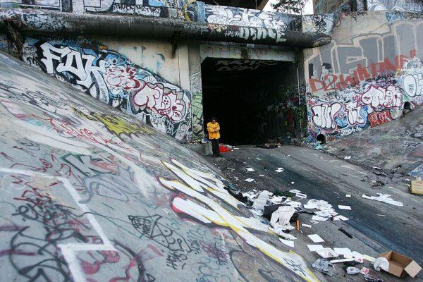 A homeless man stands next to the graffiti-covered walls that line the banks of the Los Angeles River in Los Angeles on April 21, 2006. (David McNew/Getty Images)