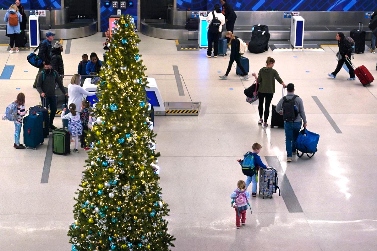 A family passes a Christmas tree while checking their bags for a flight at Logan International Airport in Boston, on Nov. 21, 2022. (Charles Krupa/AP Photo)