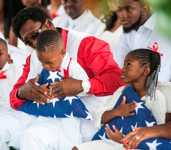 Children of U.S. Army Sgt. La David Johnson, who was killed in an ambush in Niger, hold folded American flags given to them during his burial service on Oct. 21, 2017, in Hollywood, Fla. (Gaston De Cardenas/Getty Images)
