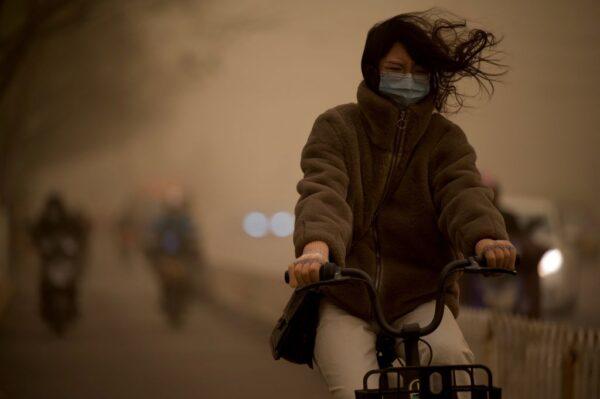 A woman cycles along a street during a sandstorm in Beijing on March 15, 2021. (Noel Celis/AFP via Getty Images)