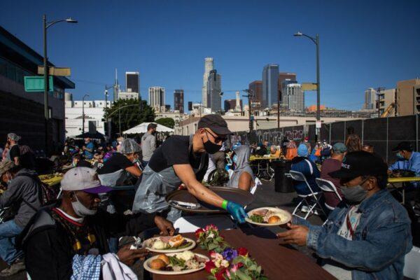 A volunteer serve a plate of food to a homeless man during the traditional Thanksgiving meal served by the non-profit Midnight Mission to nearly 2000 homeless people in the Skid Row neighborhood of downtown Los Angeles on Nov. 25, 2021. (Apu Gomes/AFP via Getty Images)