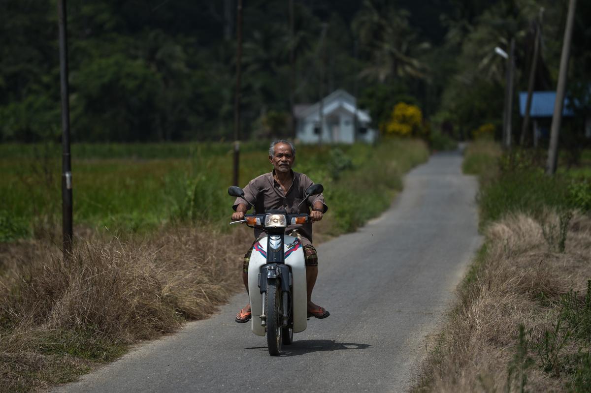 A villager rides his motorcycle down a straight, narrow road surrounded by hills and dense jungle at Wang Kelian in the northern  Malaysian state of Perlis, which borders Thailand, on May 27, 2015. (Mohd Rasfan/AFP via Getty Images)