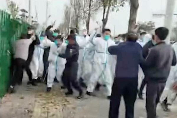 Security personnel in protective clothing attack a man during protest at the factory compound operated by Foxconn Technology Group who runs the world’s biggest Apple iPhone factory in Zhengzhou in central China’s Henan Province on Nov 23, 2022. (AP)