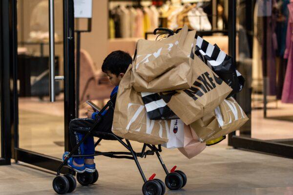 A child wait outside a shop on a trolley full of shopping bags during Black Friday sales in Chadstone Shopping Centre, in Melbourne, Australia, on Nov. 25, 2022. (AAP Image/Diego Fedele)