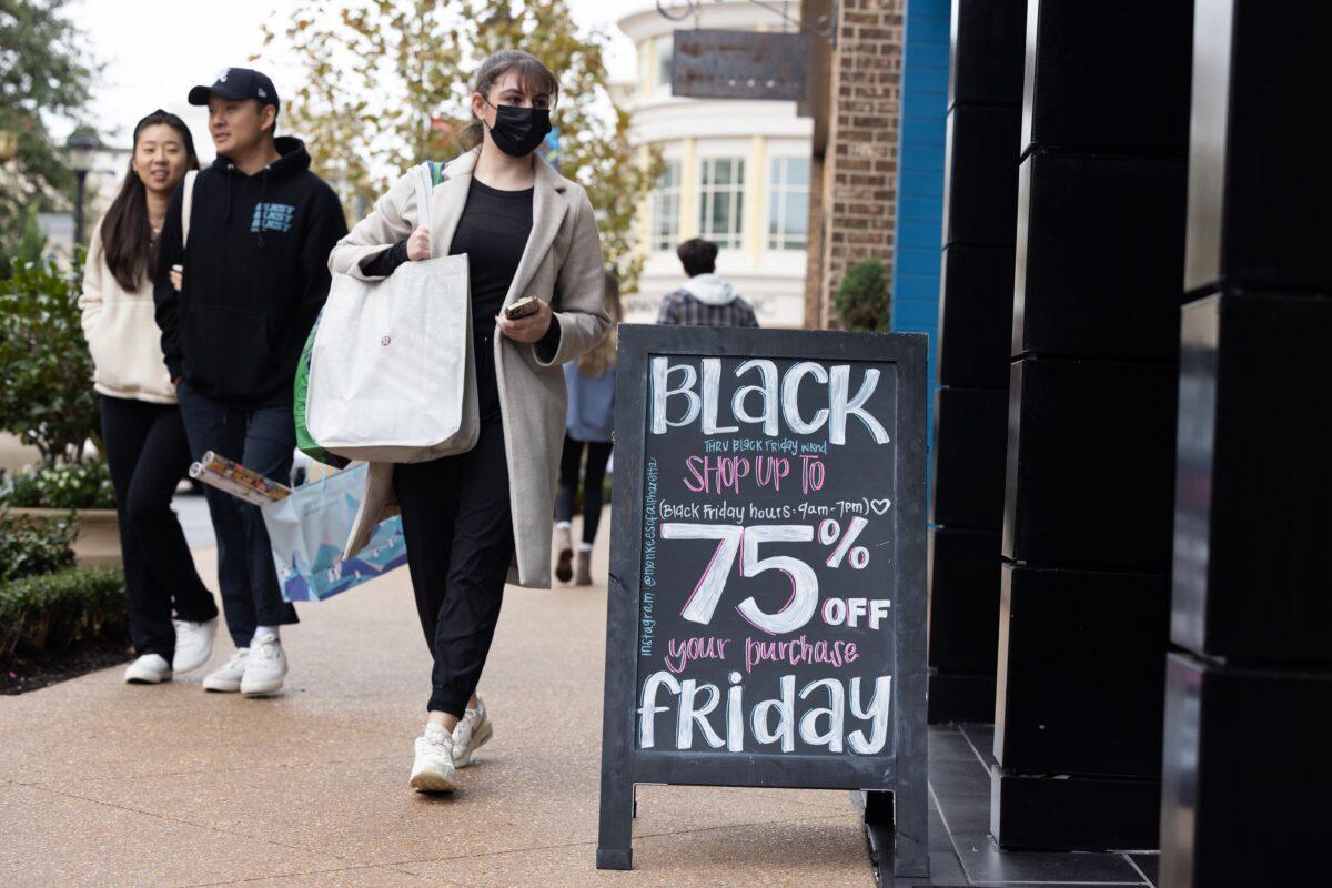 Shoppers walk past sale signs in the outdoor shopping area of Avalon during Black Friday in Alpharetta, Ga., on Nov. 25, 2022. (Jessica McGowan/Getty Images)