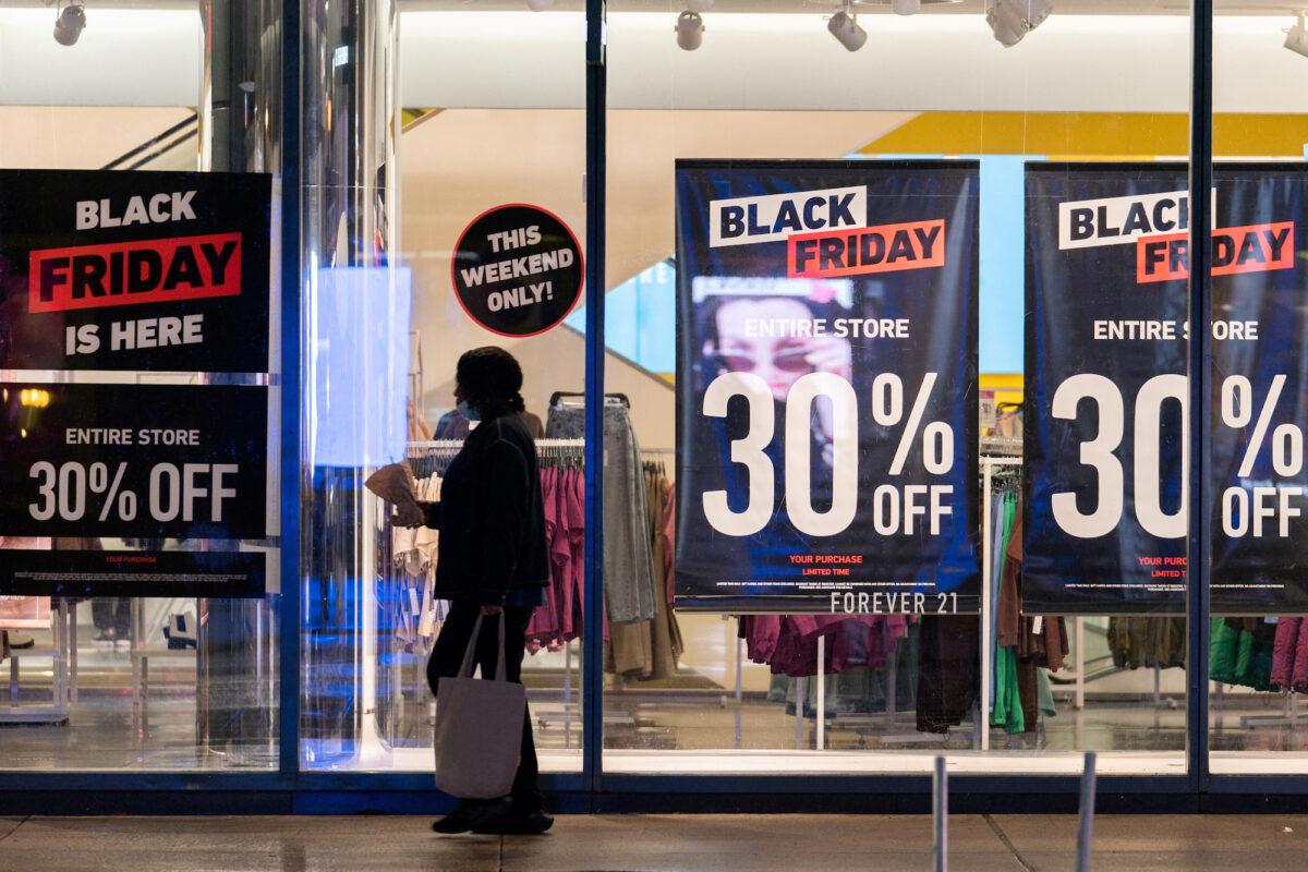 A woman passes by signs advertising sales of Black Friday in the Manhattan borough of New York on Nov. 26, 2021. (Jeenah Moon/File Photo/Reuters)