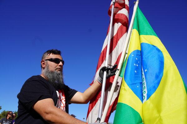 Erich, an Arizona resident, holds American and Brazilian flags at a rally to demand a new midterm election in Phoenix, Ariz., on Nov. 25, 2022. (Allan Stein/The Epoch Times)