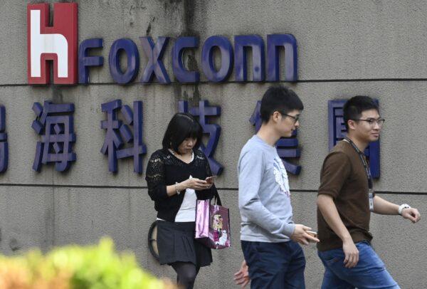 People walk past a Foxconn logo in Taipei, Taiwan, on Jan. 31, 2019. (SAM YEH/AFP via Getty Images)
