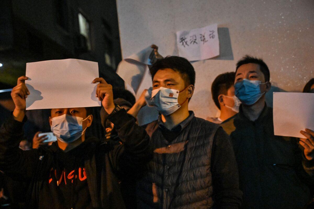 People show blank papers as a way to protest while gathering on Wulumuqi Middle Road in Shanghai on Nov. 27, 2022. (Photo by Hector RETAMAL / AFP)