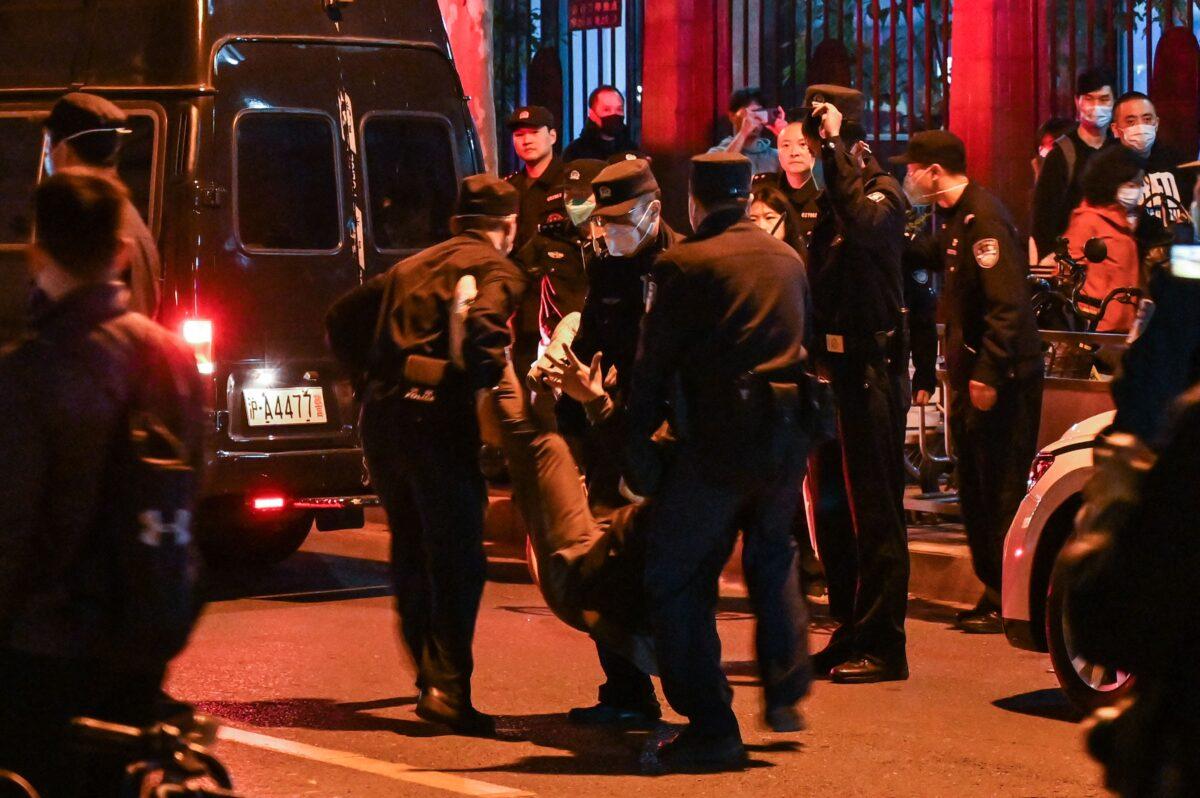 A man is arrested while people gather on a street in Shanghai where protests against China's zero-COVID policy took place the night before, following a deadly fire in Urumqi, Xinjiang, China, on Nov. 27, 2022. (Hector Retamal/AFP via Getty Images)