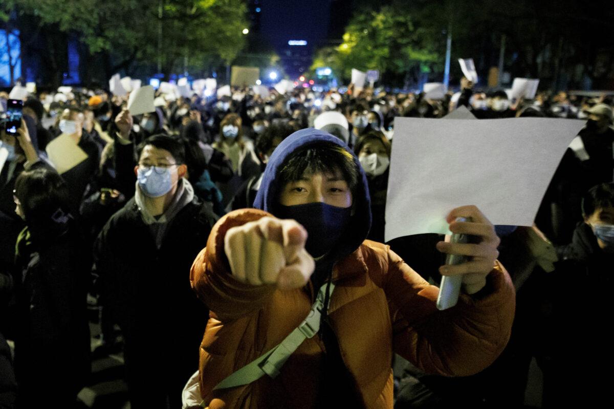 People hold white sheets of paper in protest in Beijing on Nov. 27, 2022. (Thomas Peter/Reuters)