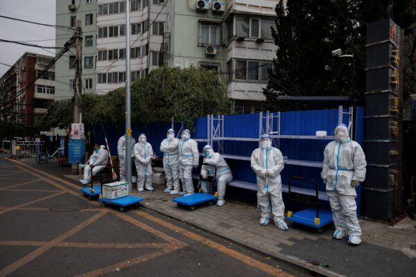 Epidemic-prevention workers in protective suits stand outside a residential compound that is under lockdown in Beijing on Nov. 28, 2022. (Thomas Peter/Reuters)