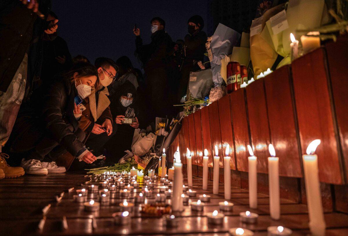 Protesters light candles and leave cigarettes at a memorial during a protest against the regime’s strict 'zero-COVID' measures in Beijing on Nov. 27, 2022. (Kevin Frayer/Getty Images)