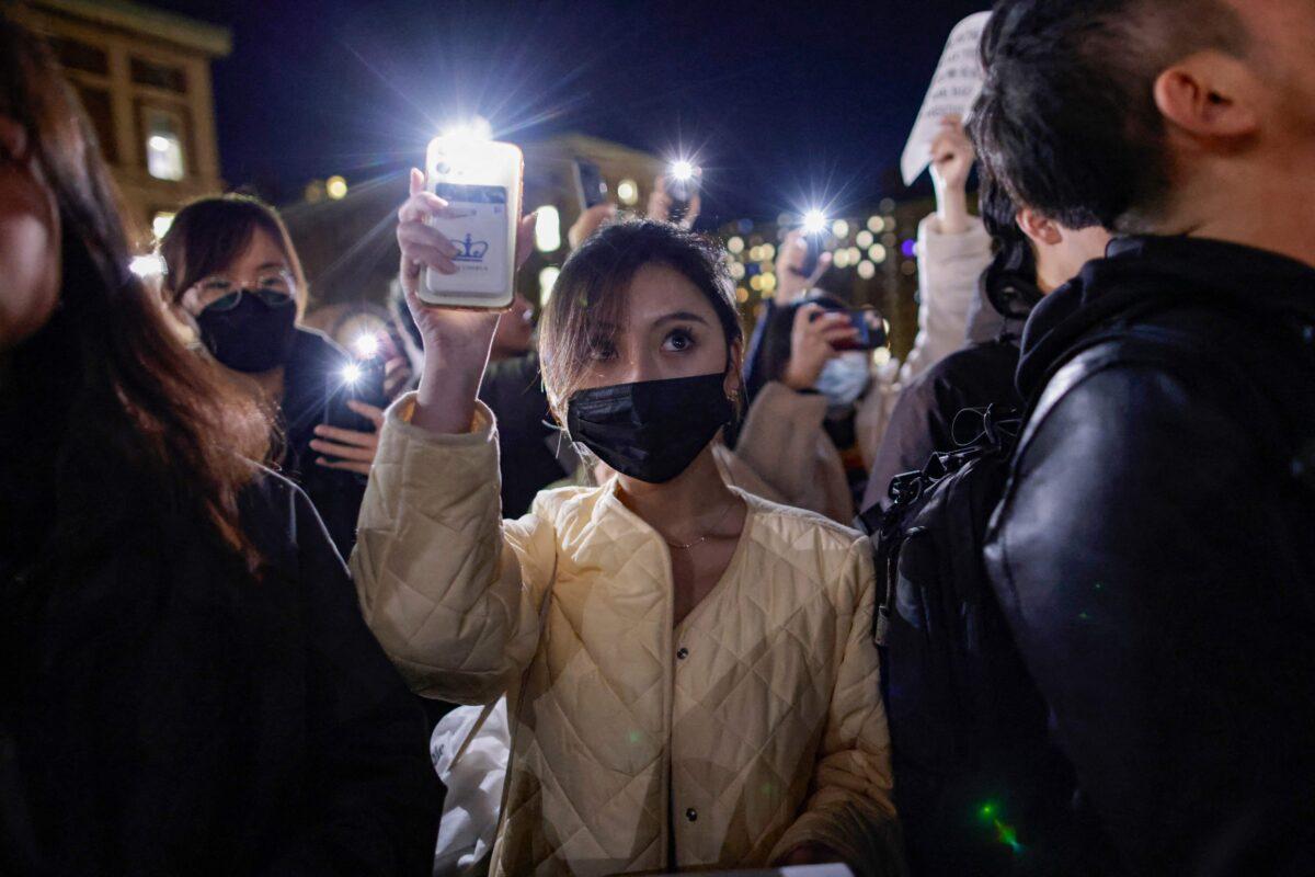 A woman holds up her phone with the flashlight on as people gather at Columbia University during a protest in support of demonstrations held in China calling for an end to COVID-19 lockdowns, in New York on Nov. 28, 2022. (Kena Betancur/AFP via Getty Images)