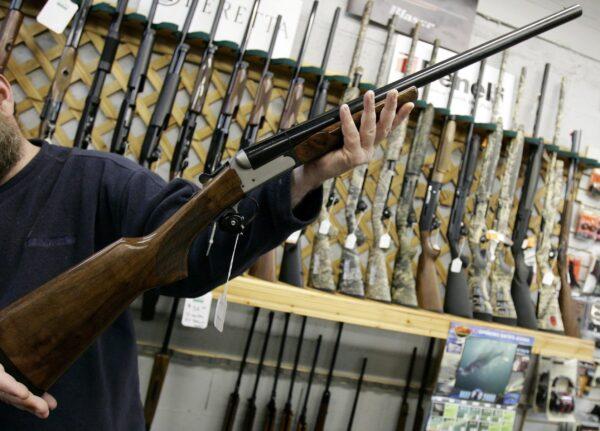 A salesman holds up a rifle at a hunting store in Ottawa, in a file photo. (Jonathan Hayward/The Canadian Press)
