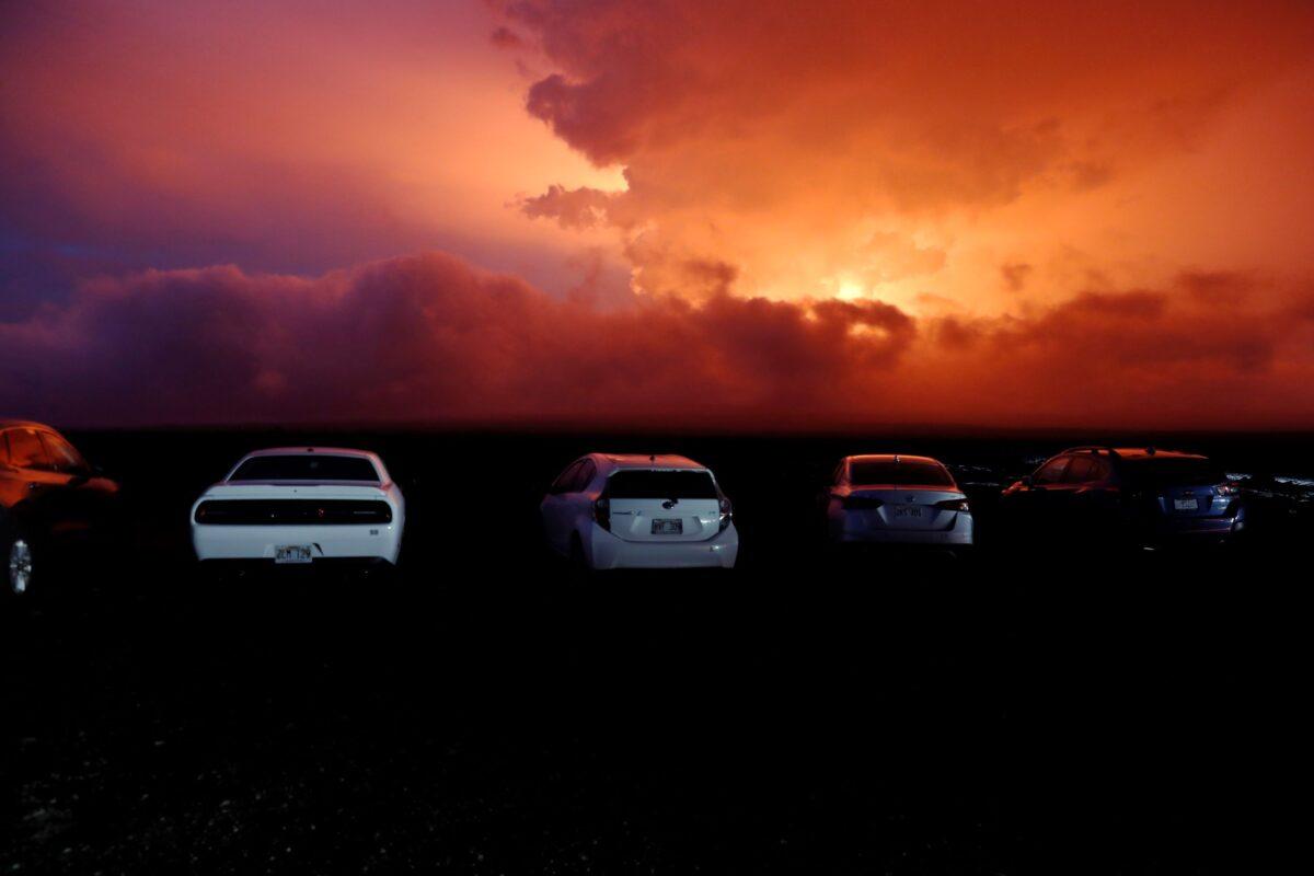 Cars are parked near an ancient lava field as a lava flow colors the sky above Mauna Loa, near Hilo, Hawaii, on Nov. 28, 2022. (Marco Garcia/AP Photo)
