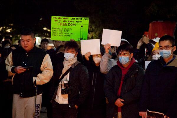 Protesters hold banners and white papers at UC Berkeley’s Sather Gate on Nov. 28, 2022. (Lear Zhou/The Epoch Times)