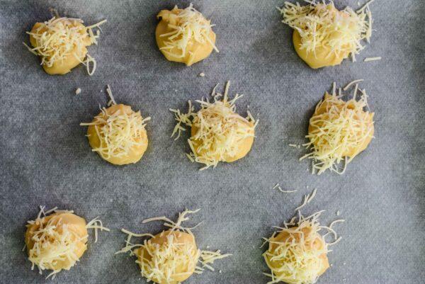 This recipe calls for topping each dough ball with grated cheese right before baking, instead of folding it into the dough, which results in lighter, airier dough with a cheesy, crackly exterior. (Courtesy of Audrey Le Goff)