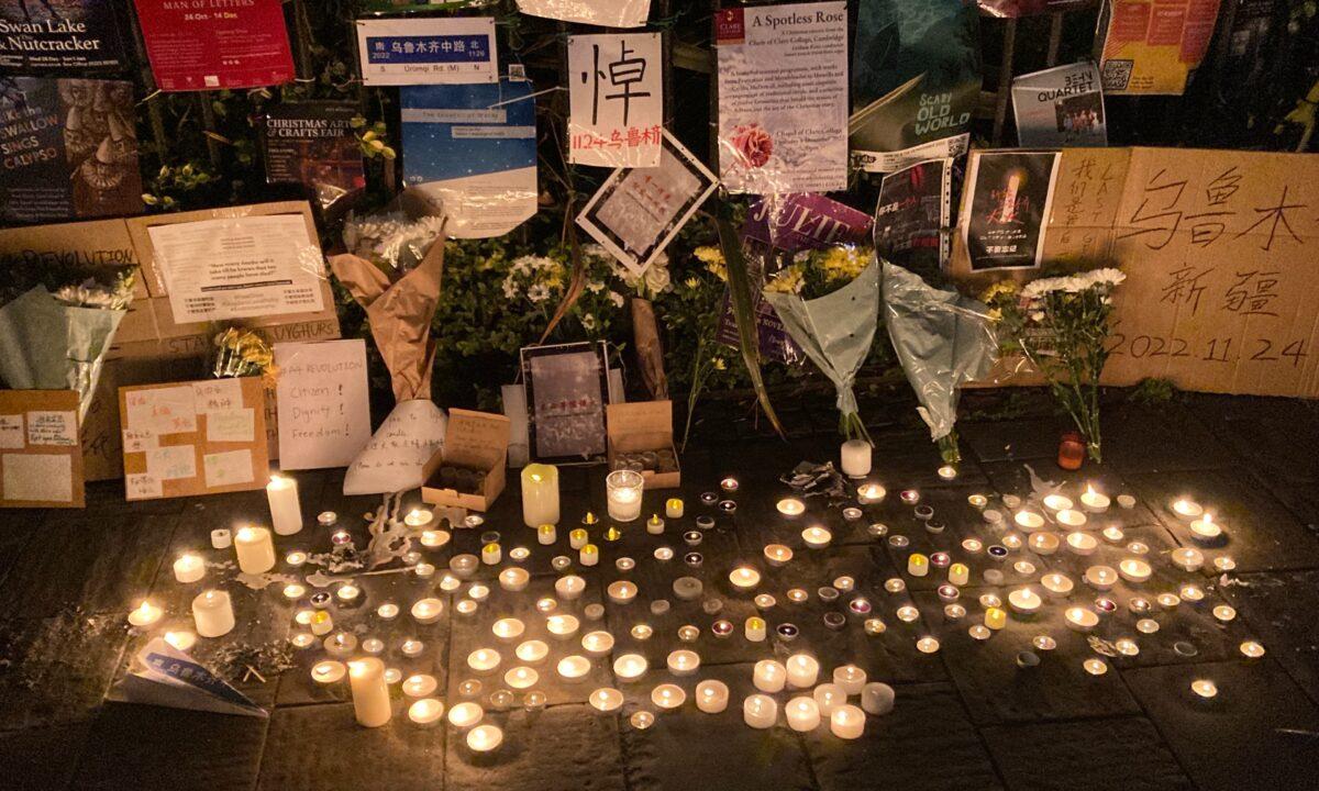 After an apartment fire in China's Xinjiang region killed at least 10 people, Placards and candles are seen at a vigil at the University of Cambridge, England, on Nov. 29, 2022. (The Epoch Times)