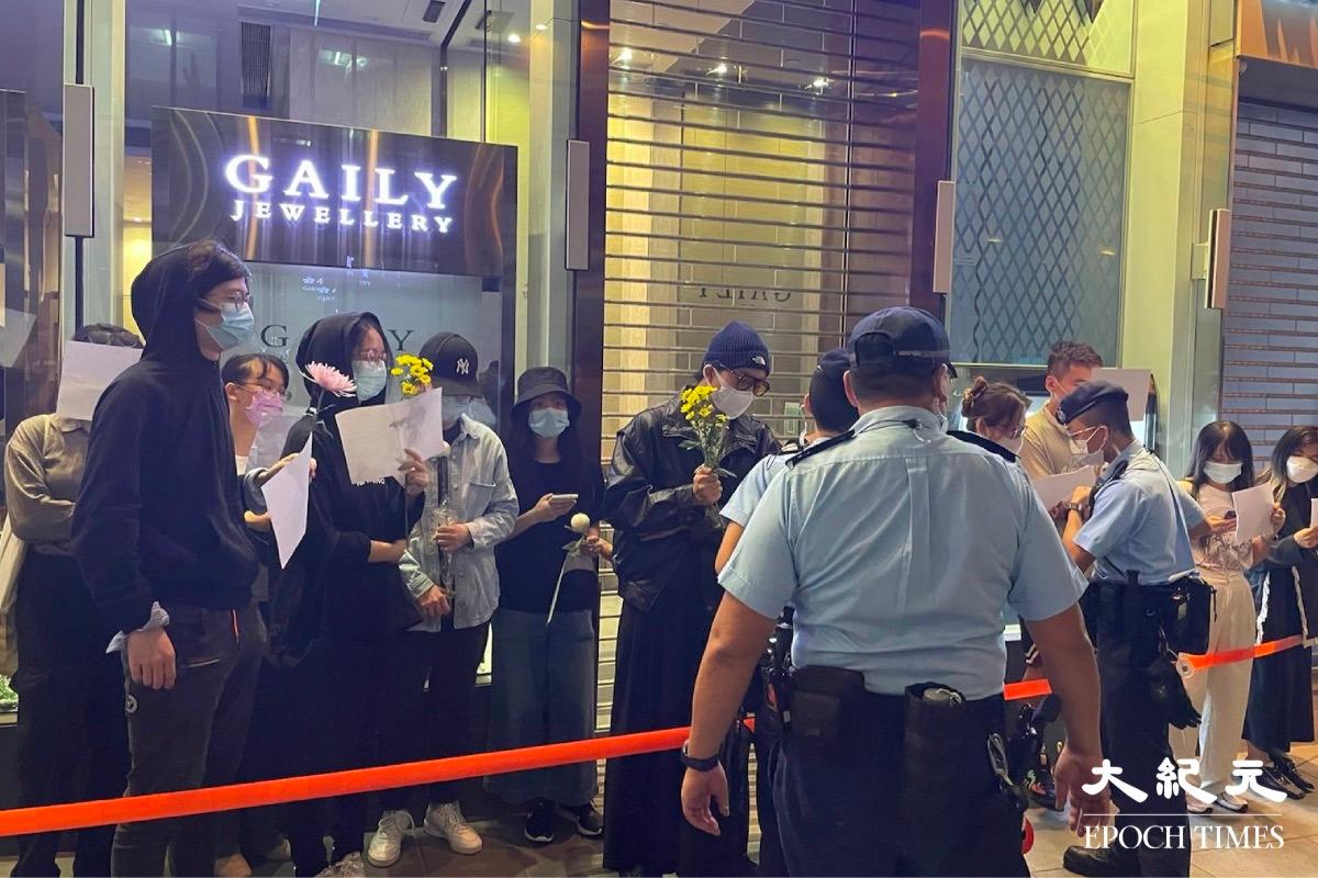 On the evening of Nov. 28, 2022, some students and citizens from mainland China in Hong Kong held a flash mob at the Central Theatre to support the "White Paper Protest" in mainland China. The police cordoned off the protesters and registered their personal information. (Cheuk Sheung-yu/The Epoch Times)