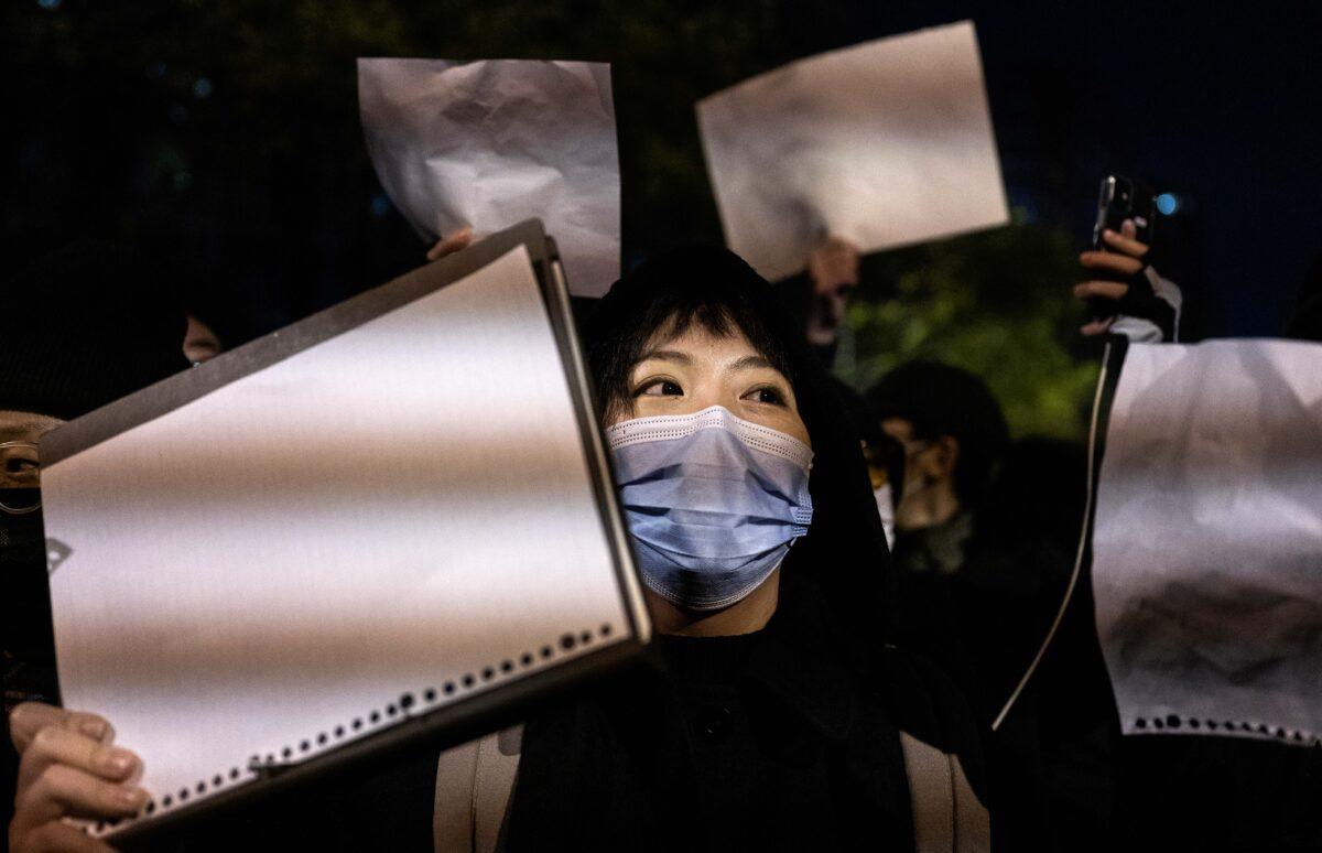 Protesters hold up a white piece of paper against censorship as they march during a protest against the Chinese regime's strict zero-COVID measures in Beijing on Nov. 27, 2022. (Kevin Frayer/Getty Images)