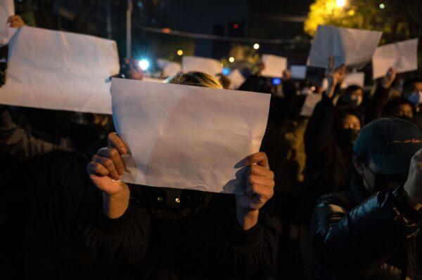Protesters hold sheets of blank white paper, denoting censorship, during a march objecting to China's strict zero-COVID measures in Beijing on Nov.27, 2022. (Kevin Frayer/Getty Images)