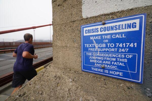 A man jogs past a sign about crisis counseling on the Golden Gate Bridge in San Francisco, Aug. 3, 2021. (Eric Risberg/AP Photo)