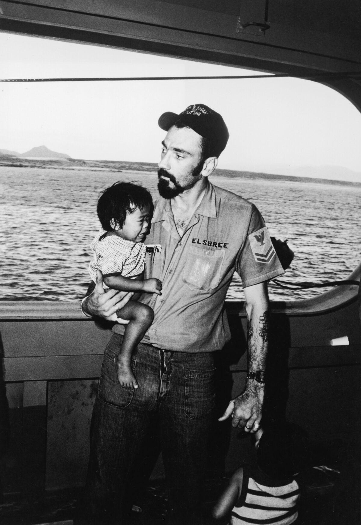 Boatswain's Mate 2nd Class Truman Elsbree of Bremerton, New York, cares for two small Vietnamese children who have been separated from their mother during the evacuation to the amphibious cargo ship USS Durham in the South China Sea, Vietnam, April 1975. The Durham evacuated more than 3,000 refugees from the Phan Rang area of Vietnam during operations on April 3 and 4, 1975. (Pictorial Parade/Getty Images)
