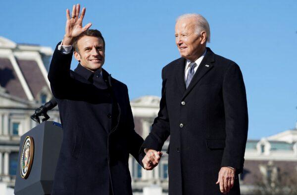 French President Emmanuel Macron waves as he holds U.S. President Joe Biden's hand onstage during an official state arrival ceremony for Macron on the South Lawn of the White House on Dec. 1, 2022. (Kevin Lamarque/Reuters)