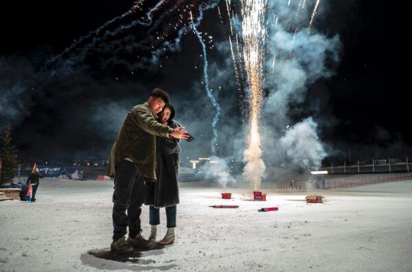 A couple take a photo as revellers fire off firecrackers to celebrate the New Year early at a ski resort in Chongli, Hebei province, China, on Jan. 1, 2023. (Kevin Frayer/Getty Images)