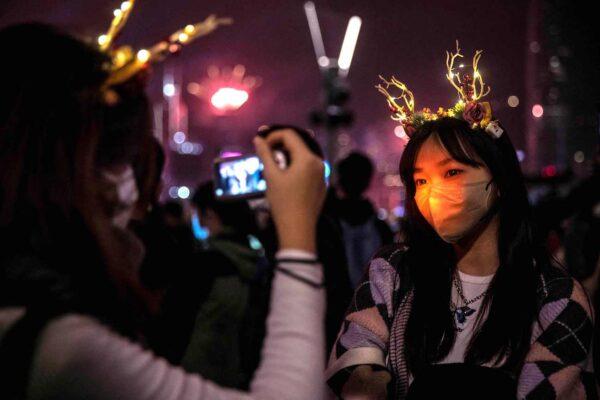 Revellers take photos during a fireworks and laser show as they celebrate the New Year next to Victoria Harbour in Hong Kong on Jan. 1, 2023. (Isaac Lawrence/AFP via Getty Images)