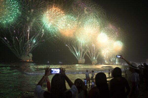People celebrate as the traditional New Year's fireworks light up the sky at Copacabana Beach in Rio de Janeiro, Brazil, on Jan. 1, 2023. (Pedro Prado/AFP via Getty Images)